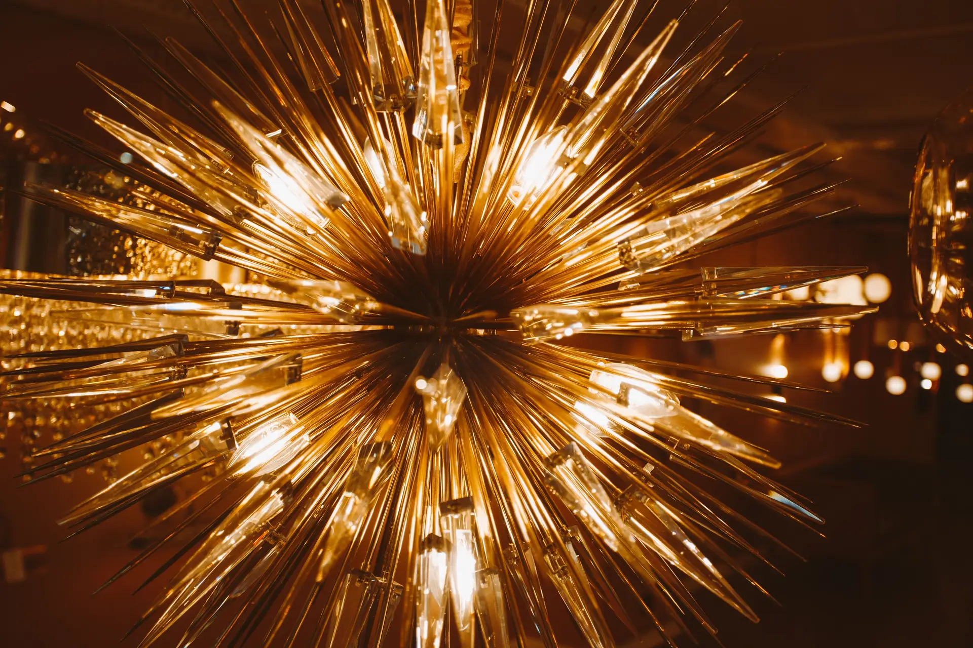 Warm starburst architectural luminaire suspended over open-plan dining space